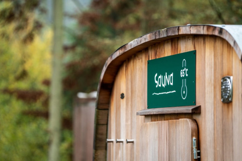 Sauna de madera con cartel de 65°C en Village Huttopia Sud-Ardèche, en Auvergne-Rhône-Alpes, Francia.