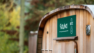 Wooden sauna with sign reading 65°C, located at Village Huttopia Sud-Ardèche in scenic Auvergne-Rhône-Alpes.