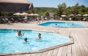 Ferieparkgæster nyder to udendørs swimmingpools med liggestole og parasoller i det solrige Sud-Ardèche.