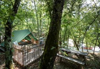 Glamping tent en picknicktafel tussen bomen bij Village Huttopia Sud-Ardèche, Auvergne-Rhône-Alpes, Frankrijk.
