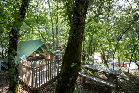 Glamping tent en picknicktafel tussen bomen bij Village Huttopia Sud-Ardèche, Auvergne-Rhône-Alpes, Frankrijk.