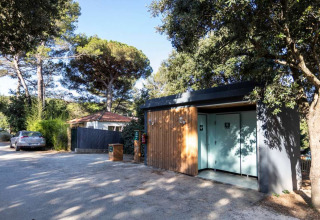 Modern sanitairgebouw tussen bomen bij Huttopia La Forêt de Janas vakantiepark in Provence-Alpes-Côte d’Azur, Frankrijk.