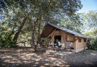 Eine Familie sitzt auf der Terrasse eines Safarizeltes bei Huttopia La Forêt de Janas in Südfrankreich.