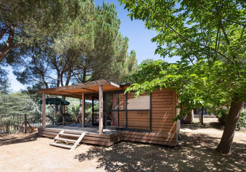 Cabaña de madera en Huttopia La Forêt de Janas, rodeada de pinos en el parque vacacional de Provenza-Alpes-Costa Azul, Francia.