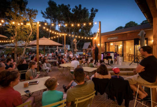 Avondevenement buiten met families en kinderen onder lichtslingers bij Huttopia La Forêt de Janas, Provence.