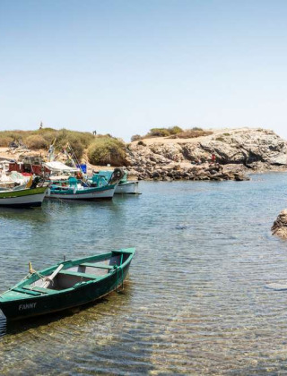 Pequeños barcos pesqueros anclados en aguas claras cerca de rocas en La Seyne-sur-Mer, Provenza, Francia.