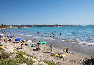Zandstrand bij La Seyne-sur-Mer, Provence-Alpes-Côte d’Azur, Frankrijk, met gezinnen die zwemmen en zonnen.