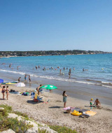 Playa cerca de La Seyne-sur-Mer, Provenza-Alpes-Costa Azul, Francia, con bañistas y familias disfrutando del sol.