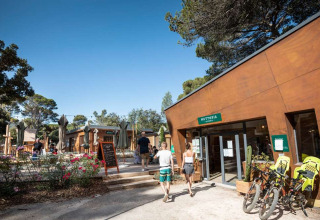 Ferienpark Huttopia La Forêt de Janas in Provence-Alpes-Côte d’Azur mit Gästen und Fahrrädern draußen.
