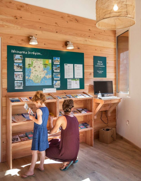 Moeder en dochter bladeren door brochures bij Huttopia La Forêt de Janas vakantiepark in Frankrijk.