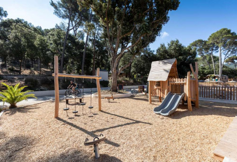Área de juegos con estructuras de madera y tobogán en Huttopia La Forêt de Janas, Provenza-Alpes-Costa Azul.
