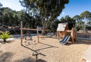 Speelplein met houten speeltoestellen en glijbaan bij Huttopia La Forêt de Janas in Provence-Alpes-Côte d’Azur.