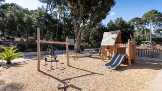 Área de juegos con estructuras de madera y tobogán en Huttopia La Forêt de Janas, Provenza-Alpes-Costa Azul.