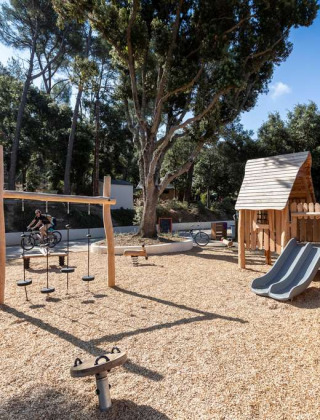 Área de juegos con estructuras de madera y tobogán en Huttopia La Forêt de Janas, Provenza-Alpes-Costa Azul.
