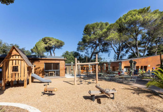 Speeltuin met houten huisje en schommels bij Huttopia La Forêt de Janas in Provence-Alpes-Côte d’Azur, Frankrijk.