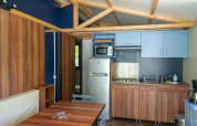 Vista interior del Chalet Evasion en Huttopia La Forêt de Janas, Francia, con cocina y comedor modernos.