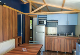 Vista interior del Chalet Evasion en Huttopia La Forêt de Janas, Francia, con cocina y comedor modernos.