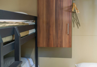 Innenraum von Chalet Evasion in Huttopia La Forêt de Janas in Frankreich mit Etagenbett, Einzelbett und Schrank.