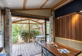 Vista interna accogliente dello Chalet Evasion con accesso alla terrazza in legno a Huttopia La Forêt de Janas, Francia.