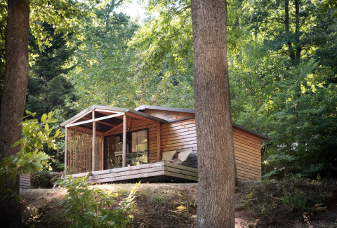 Cabaña Chalet Evasion en Huttopia La Forêt de Janas, Francia, rodeada de árboles verdes y naturaleza.