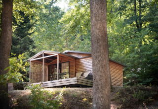 Cabaña Chalet Evasion en Huttopia La Forêt de Janas, Francia, rodeada de árboles verdes y naturaleza.
