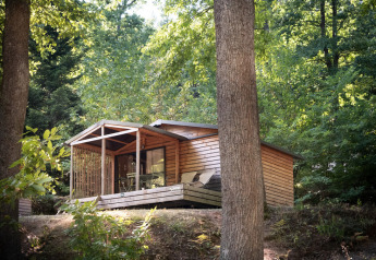Chalet Evasion à Huttopia La Forêt de Janas, France, cabane en bois entourée de forêt verdoyante.