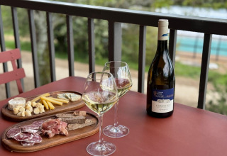 Vin og charcuteri på altanbord med udsigt på Village Huttopia Pays de Condrieu, Auvergne-Rhône-Alpes, Frankrig.