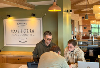 Receptionister hjælper gæst ved ankomsten til Village Huttopia Pays de Condrieu i Auvergne-Rhône-Alpes, Frankrig.