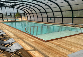Indendørs swimmingpool med liggestole og trædæk på Village Huttopia Pays de Condrieu i Frankrig.