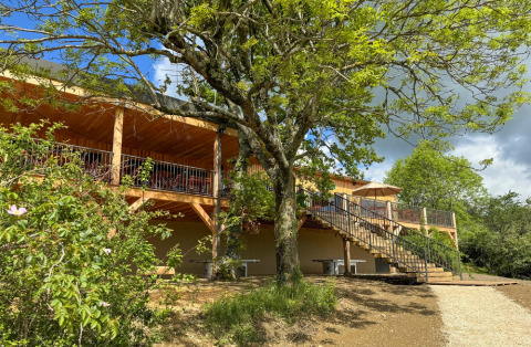 Terrasse extérieure en bois du Village Huttopia Pays de Condrieu entourée d’arbres en Auvergne-Rhône-Alpes.