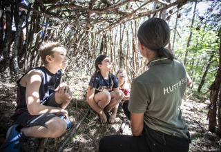 Children and an adult in a forest hut at Village Huttopia Pays de Condrieu holiday park in Auvergne-Rhône-Alpes, France.