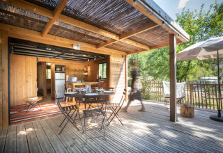 Træterrasse med spisebord og stole på Village Huttopia Pays de Condrieu i Auvergne-Rhône-Alpes, Frankrig.