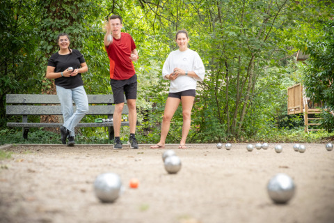 Drie jongeren spelen petanque buiten in Village Huttopia Pays de Condrieu, Auvergne-Rhône-Alpes, Frankrijk.
