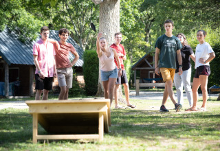 Jugendliche spielen zusammen ein Outdoor-Spiel im Sonnenschein im Urlaubsort Village Huttopia Pays de Condrieu.