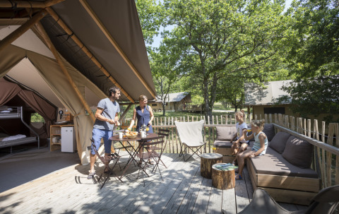 Familia desayunando en la terraza de una tienda glamping en Village Huttopia Pays de Condrieu, Francia.