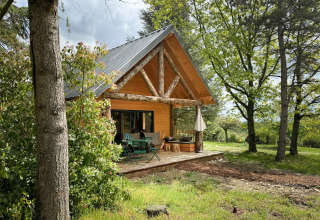Gemütliche Holzhütte mit Terrasse im Grünen im Village Huttopia Pays de Condrieu, Auvergne-Rhône-Alpes, Frankreich.