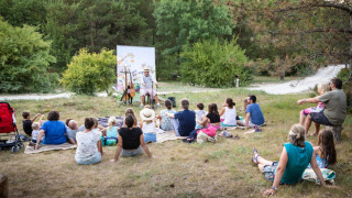 Familias disfrutan de un espectáculo al aire libre en Village Huttopia Pays de Condrieu, parque vacacional francés.
