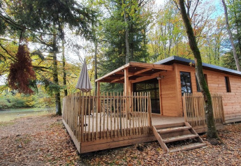 Houten Chalet Toronto in Village Huttopia Pays de Condrieu, Frankrijk, omringd door een herfstbos.