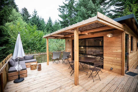 Holzterrasse des Chalet Toronto im Village Huttopia Pays de Condrieu, umgeben von Bäumen, Frankreich.