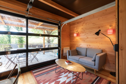 Sala de estar en chalet de madera con puerta de vidrio y vista al exterior en Chalet Toronto, Francia.