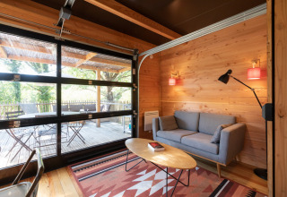 Moderne træhytte stue med glasdør til terrasse og naturudsigt i Chalet Toronto, Frankrig.