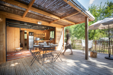 Houten terras met tuintafel en stoelen bij Chalet Toronto, Village Huttopia Pays de Condrieu, Frankrijk.
