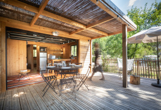 Houten terras met tuintafel en stoelen bij Chalet Toronto, Village Huttopia Pays de Condrieu, Frankrijk.