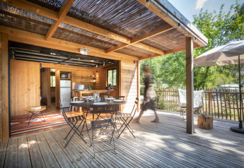Terrazza in legno con tavolo da pranzo presso Chalet Toronto, Village Huttopia Pays de Condrieu, Francia.