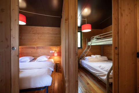 Indvendigt billede af Chalet Toronto på Village Huttopia Pays de Condrieu med dobbeltseng og køjeseng.