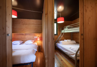 Interieur van Chalet Toronto bij Village Huttopia Pays de Condrieu met een dubbel bed en een stapelbed.