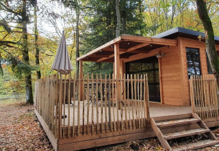 Træhytte kaldet Chalet Toronto ved søen i Village Huttopia Pays de Condrieu, Frankrig, omgivet af skov.