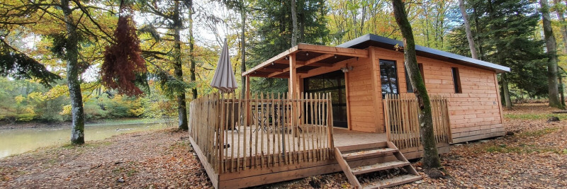 Cabaña de madera Chalet Toronto en Village Huttopia Pays de Condrieu, Francia, rodeada de árboles junto al lago.