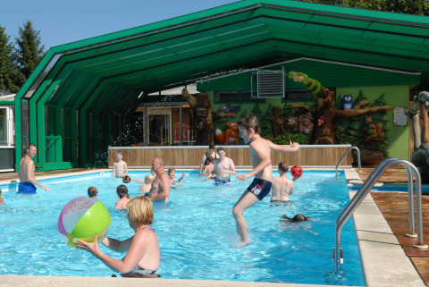 Kids and adults play in the pool at Veluwecamping De Pampel holiday park in Gelderland, Netherlands, sunny day.