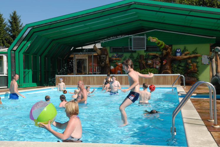 Kids and adults play in the pool at Veluwecamping De Pampel holiday park in Gelderland, Netherlands, sunny day.